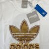 T-shirt oversize Adidas  Iconic 1963 bianca con dettagli oro, perle e strass